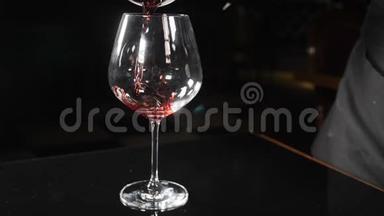 红酒在黑色背景下倒入酒杯中，慢动作。 将红酒从瓶颈倒入玻璃杯中。 关闭